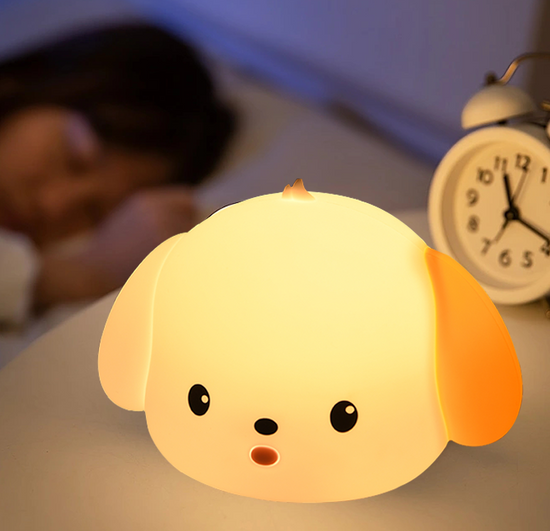 Spotted Puppy Night Light glowing softly on bedside table with alarm clock and sleeping child in background